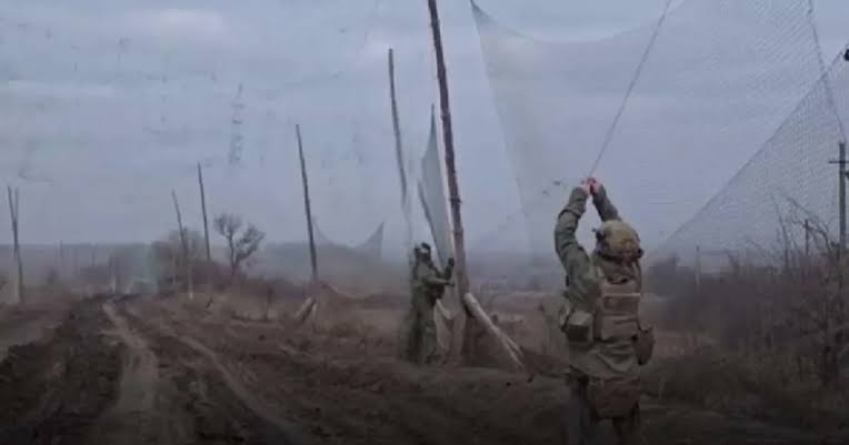 Soldiers installing anti-drone netting over a road